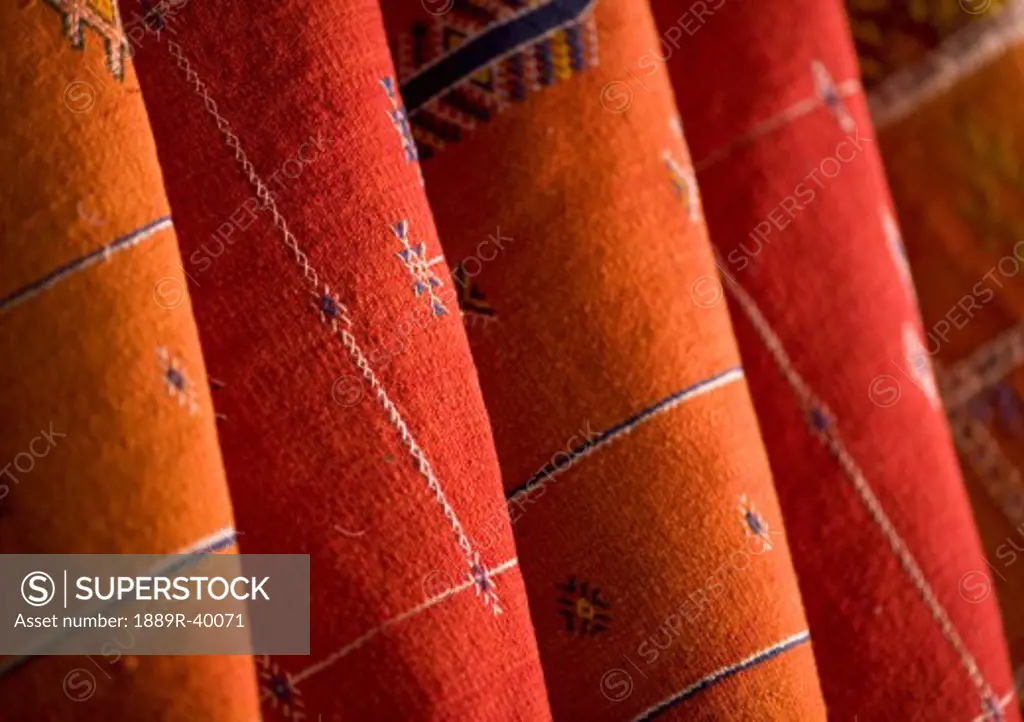 Red and orange Morrocan rugs hung for sale in the souks of Marrakech, Morocco  