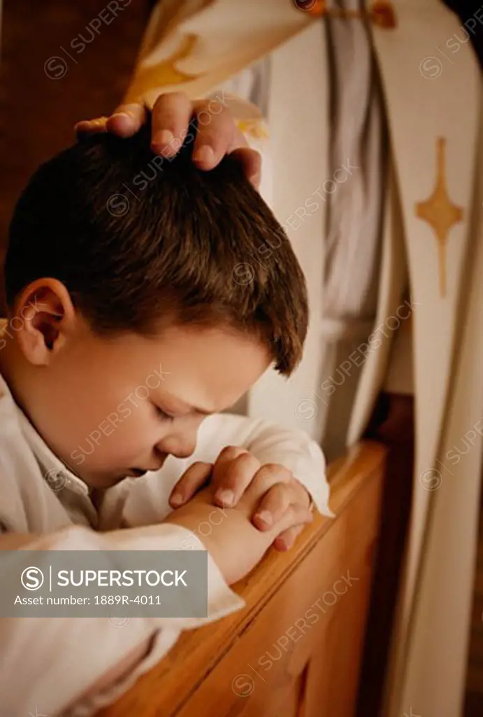 Priest praying for young boy