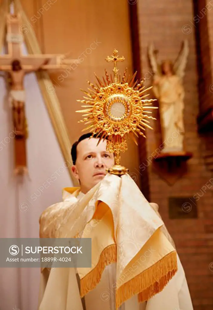 Priest holding up gold pillar