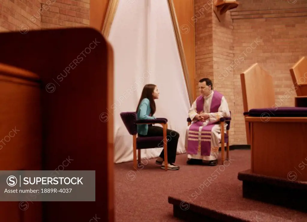 Priest with young woman in church