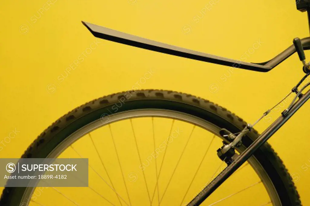 Rear bicycle wheel against yellow background