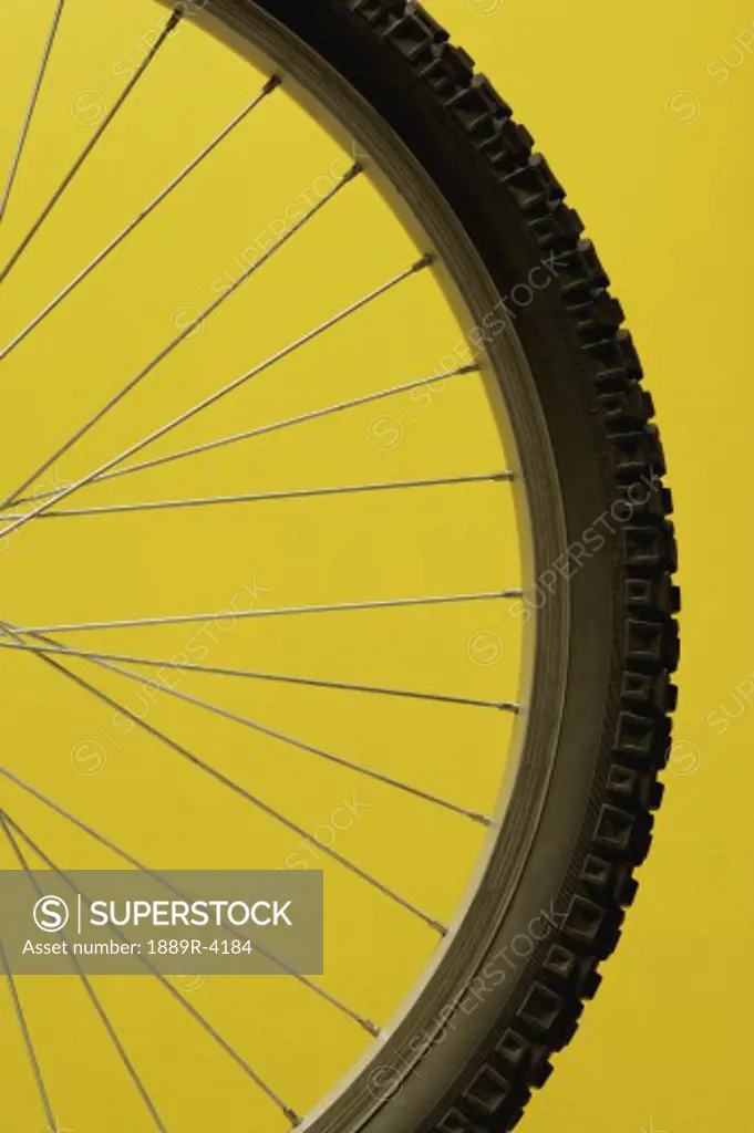 Part of a bicycle wheel against yellow background