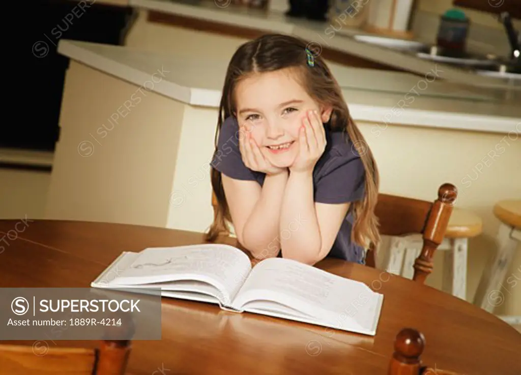 Young girl sat at the kitchen table reading