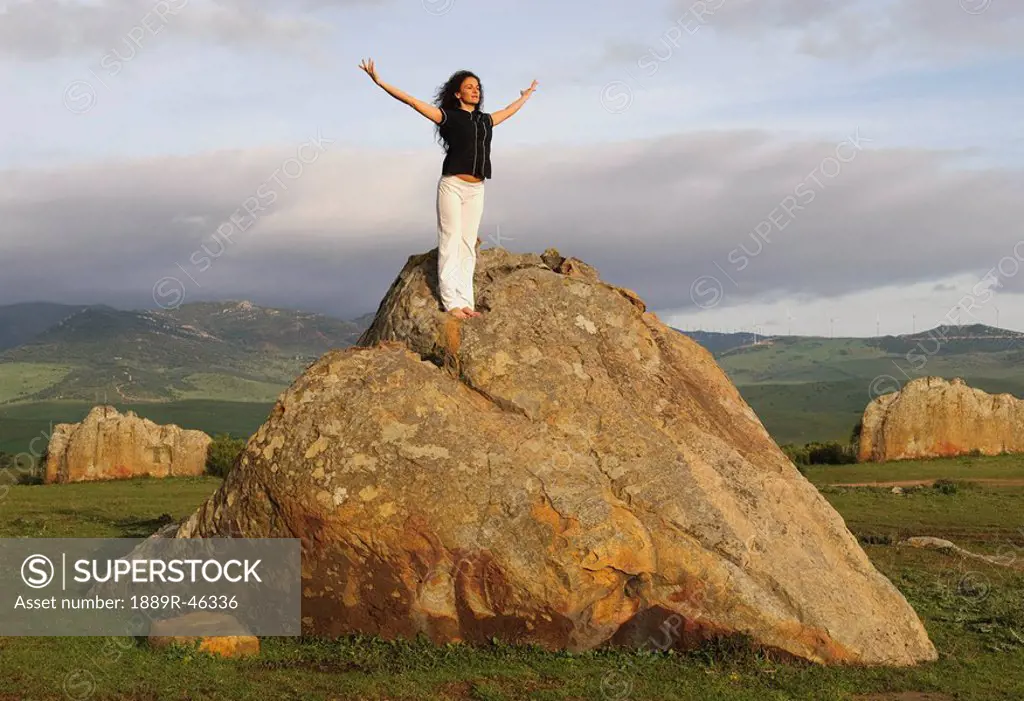 Woman on large boulder in yoga pose