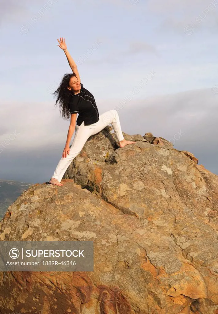 Woman in yoga position on large boulder