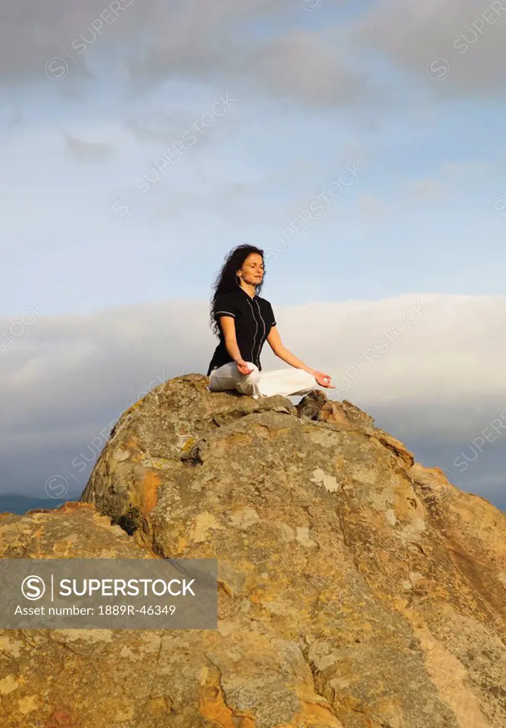 Woman meditating on a boulder