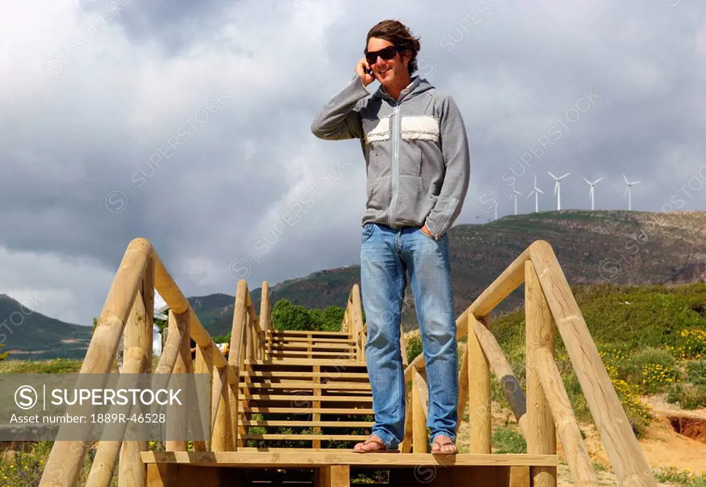 Man on the phone and standing on wooden stairs