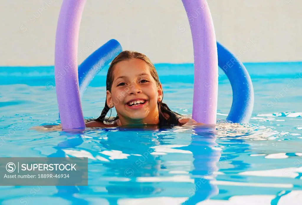 Girl in pool with pool noodles