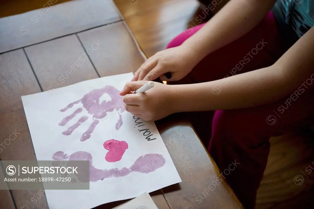 Girl making hand and footprints on paper