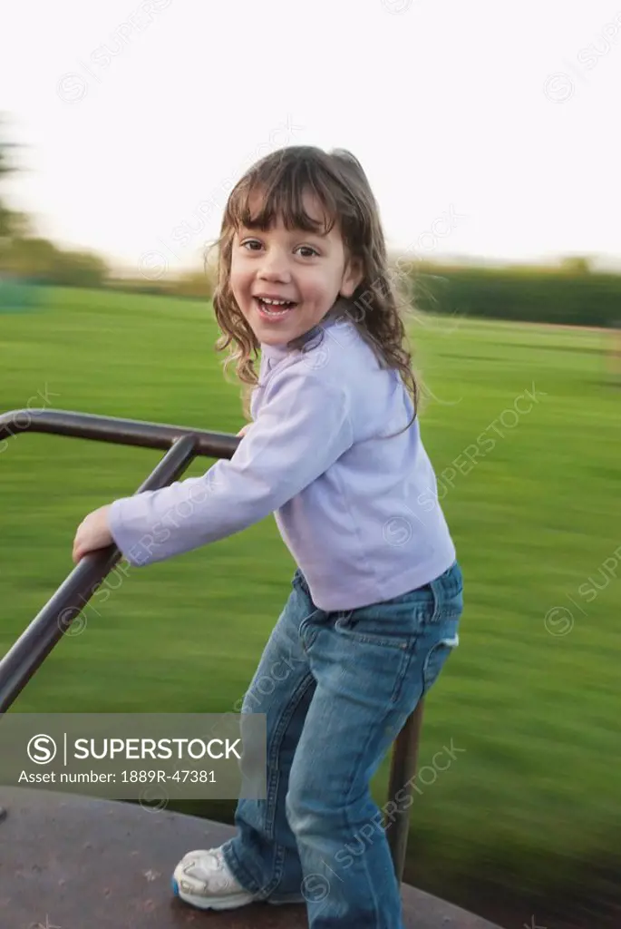 Three year old girl playing on merry_go_round