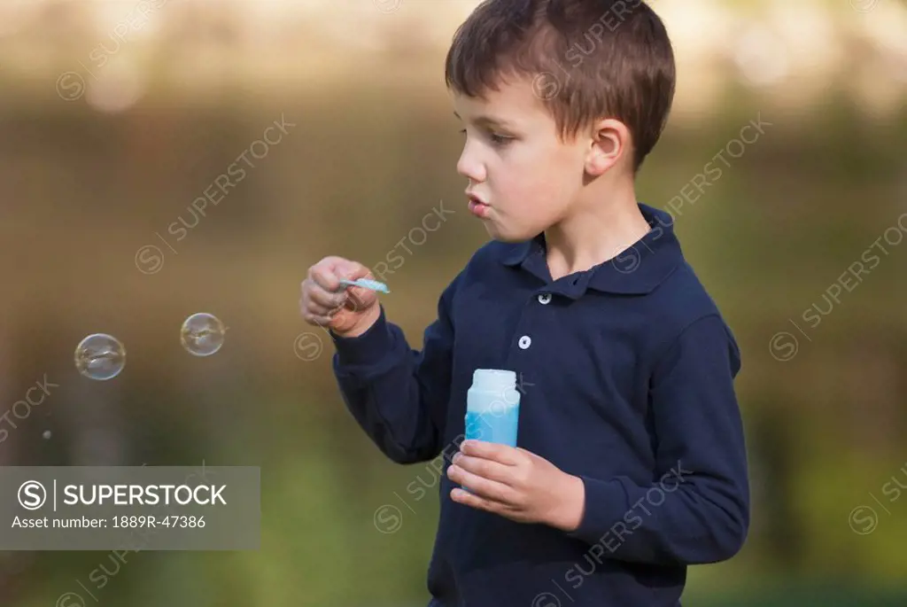 Five year old boy blowing bubbles
