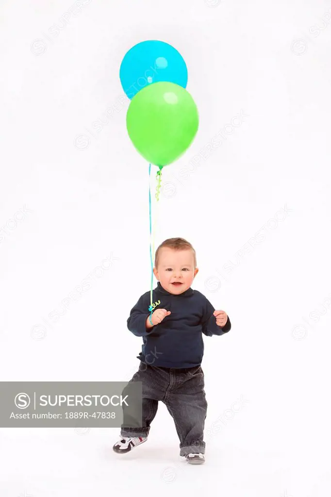 Boy walking with two balloons