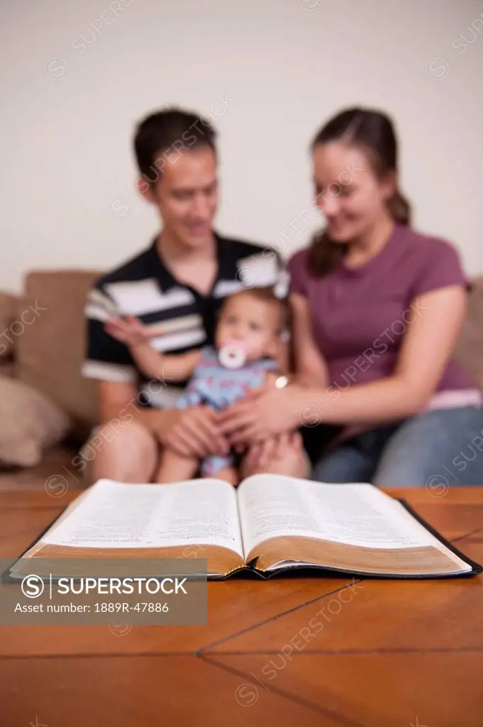 A family with a Bible on the coffee table