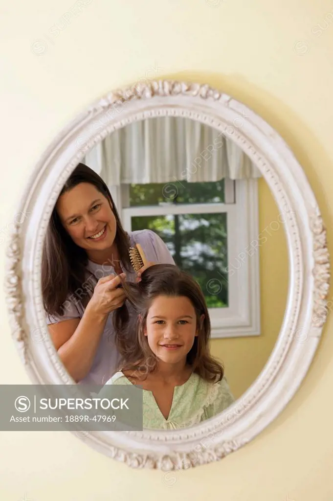 A mother helping her daughter do her hair