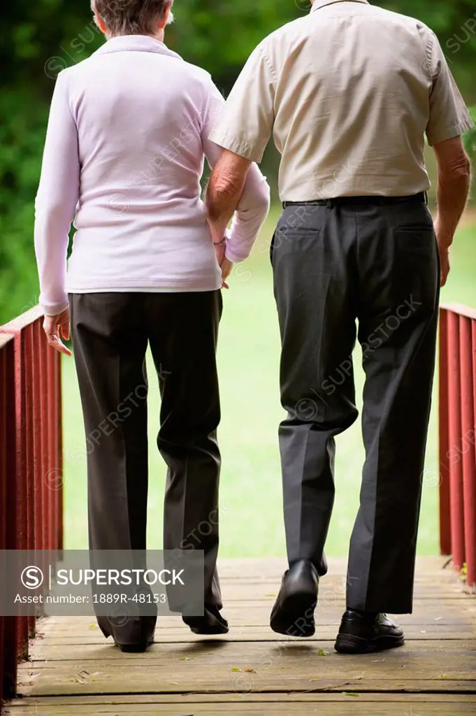 An elderly couple walking across a bridge