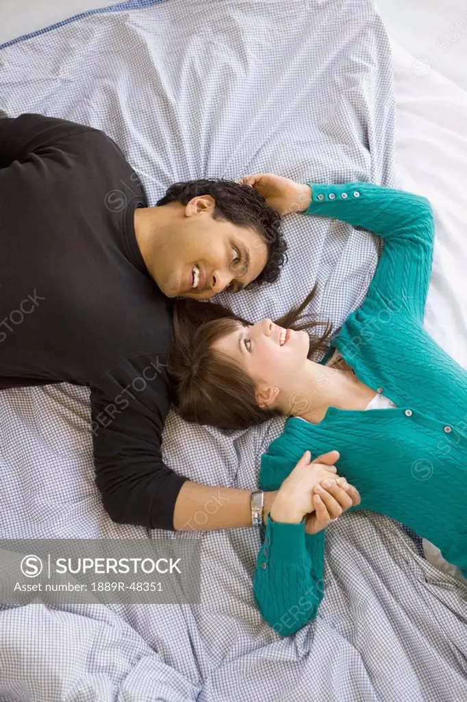 Young happy interracial couple lying on bed