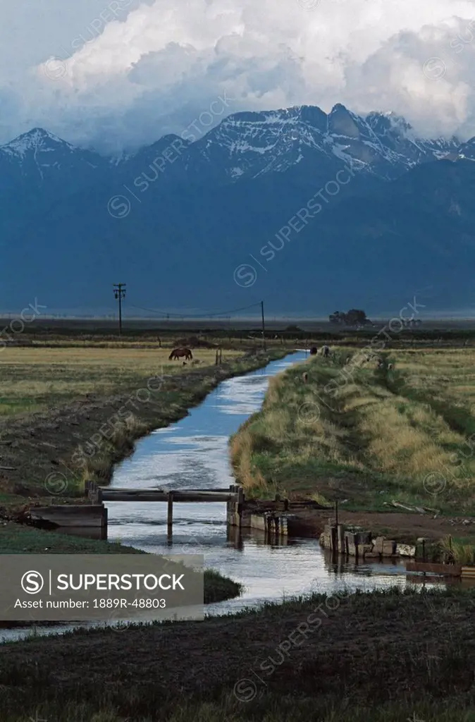 Irrigation canal with mountains and storm clouds in the background