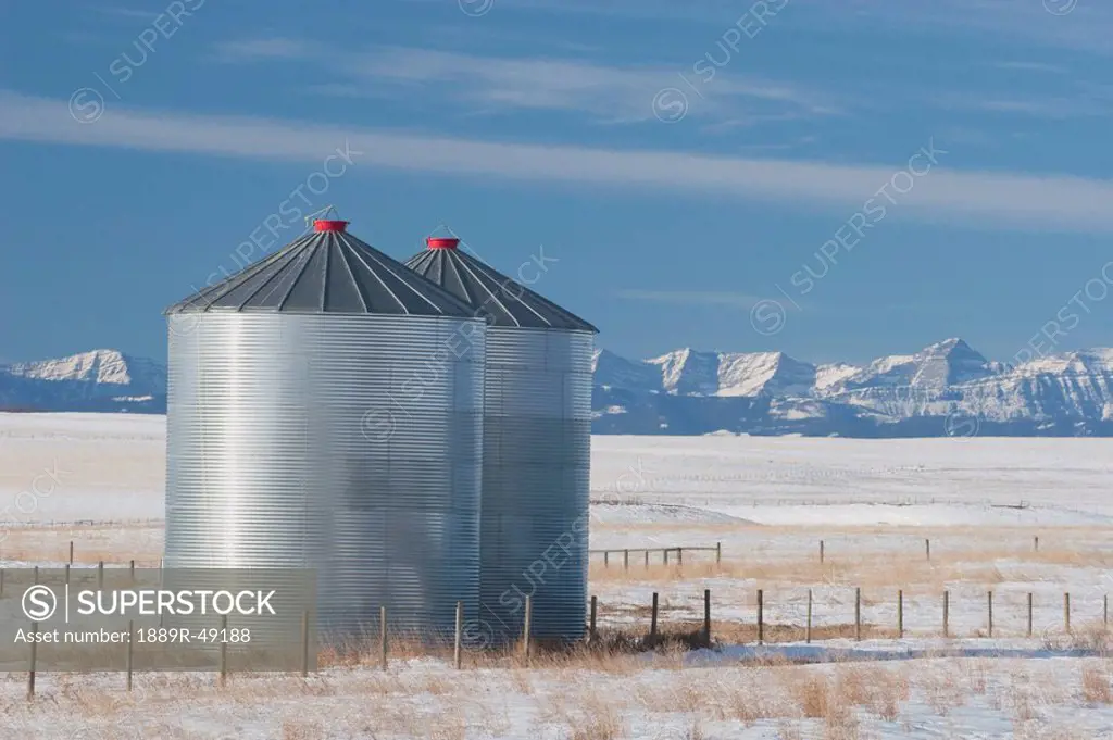 Metal grain bins in snowy field, Alberta, Canada
