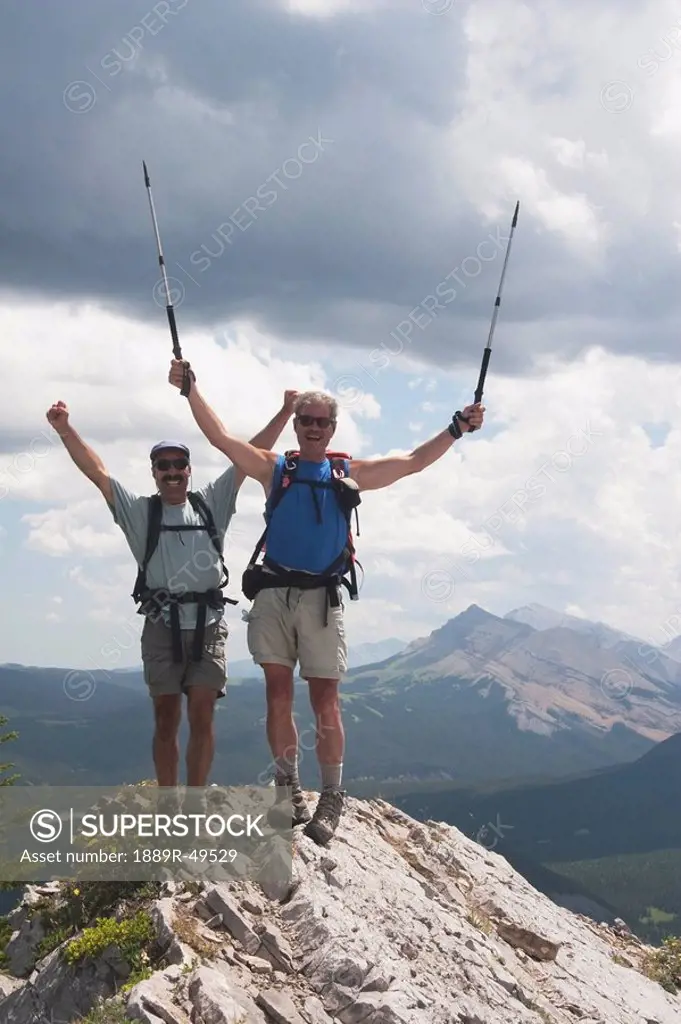 Two men cheering at the top of a mountain