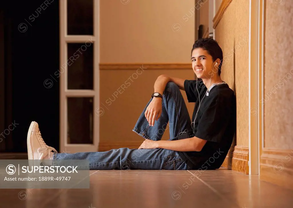 Teenage boy sitting on the floor listening to music