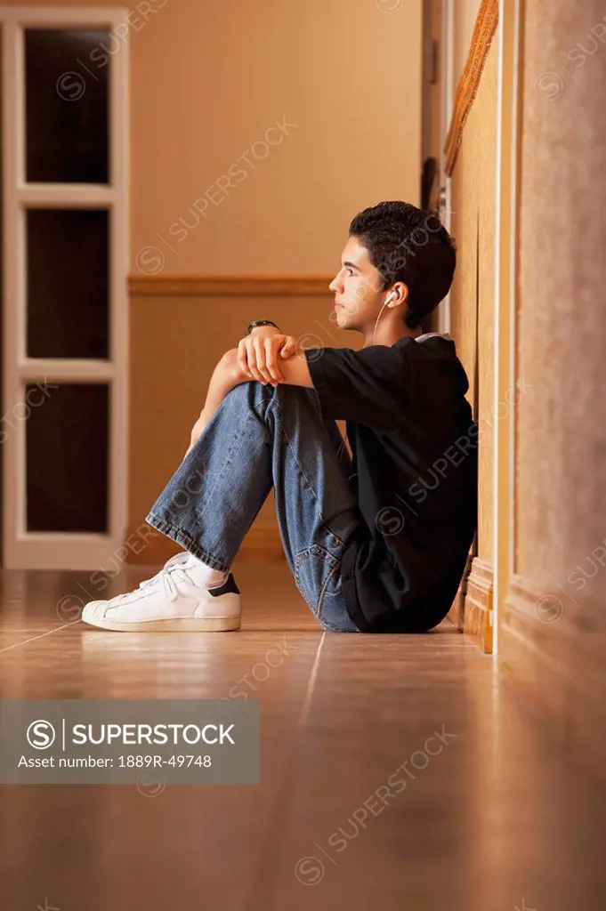 Teenage boy sitting on the floor listening to music