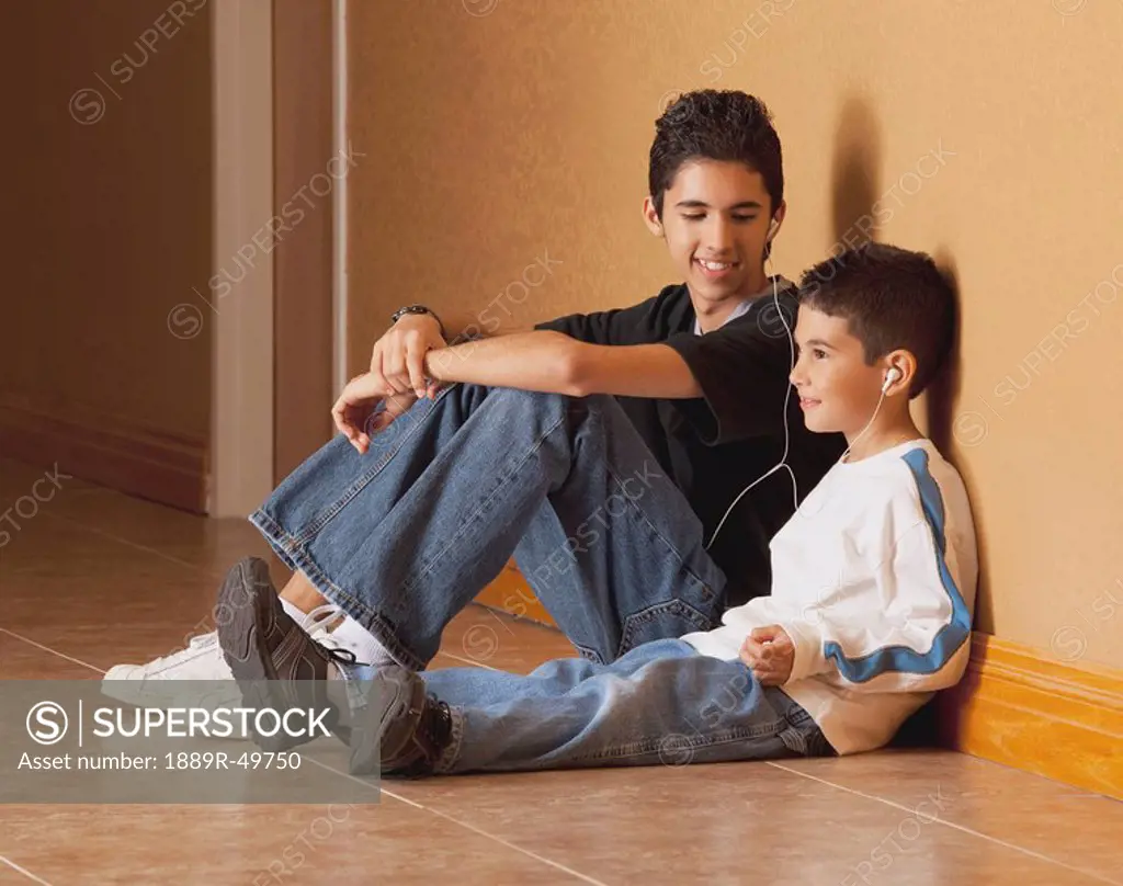 Brothers sitting on the floor listening to music