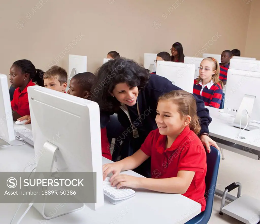 teacher helping student in computer class