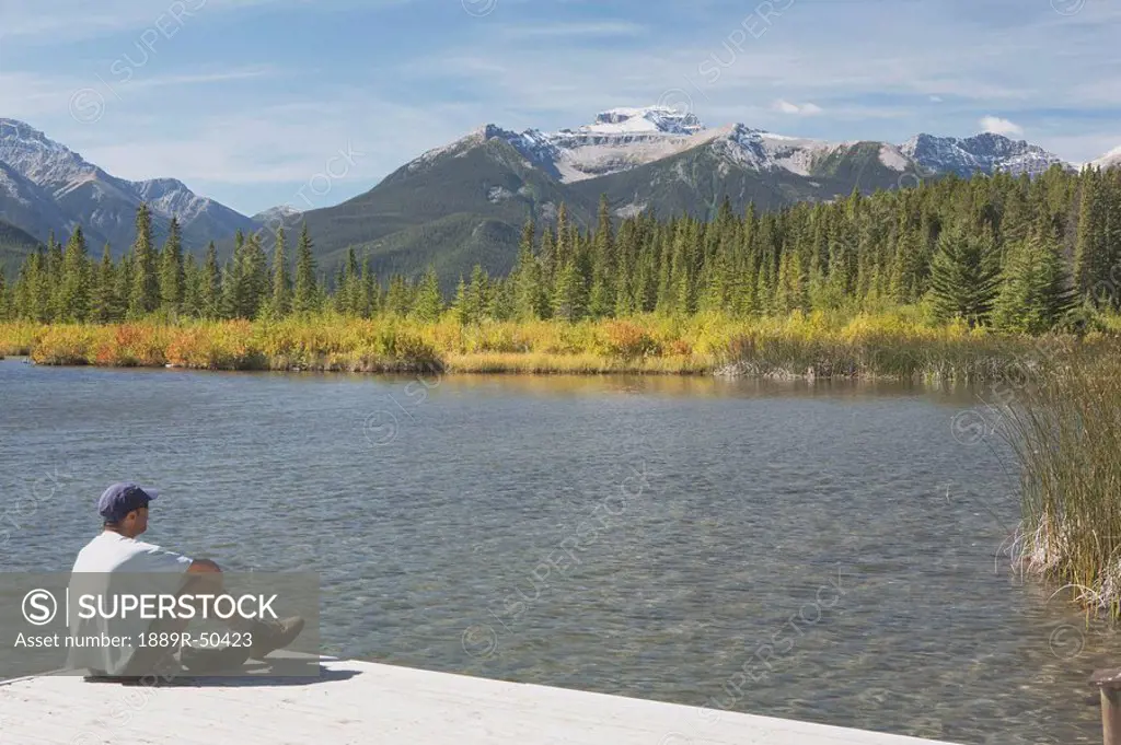 banff national park, alberta, canada, a man sitting on a dock at vermilion lakes