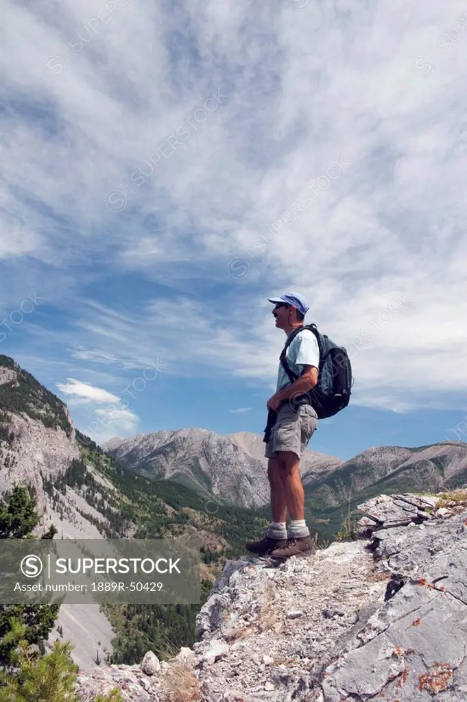 crowsnest pass, alberta, canada, a male hiker standing on a ridge looking at turtle mountain
