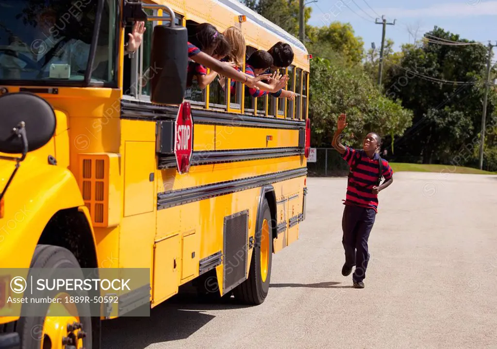 student running and waving goodbye to friends on the school bus