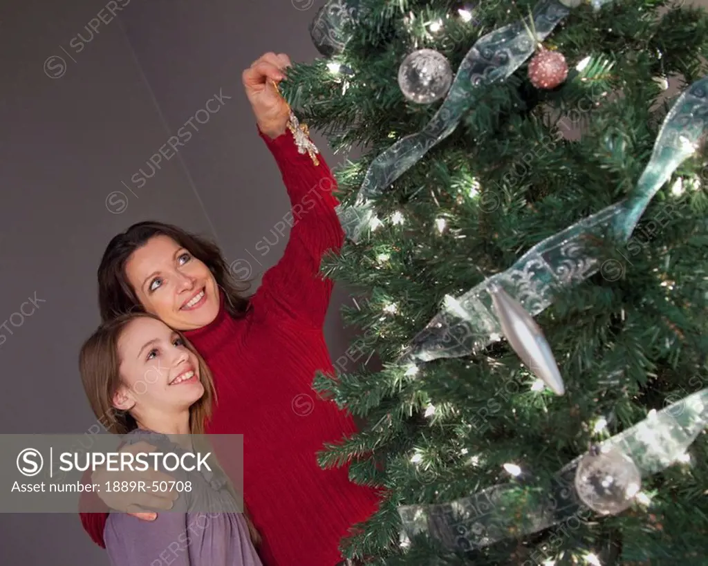 mother and daughter decorating the christmas tree