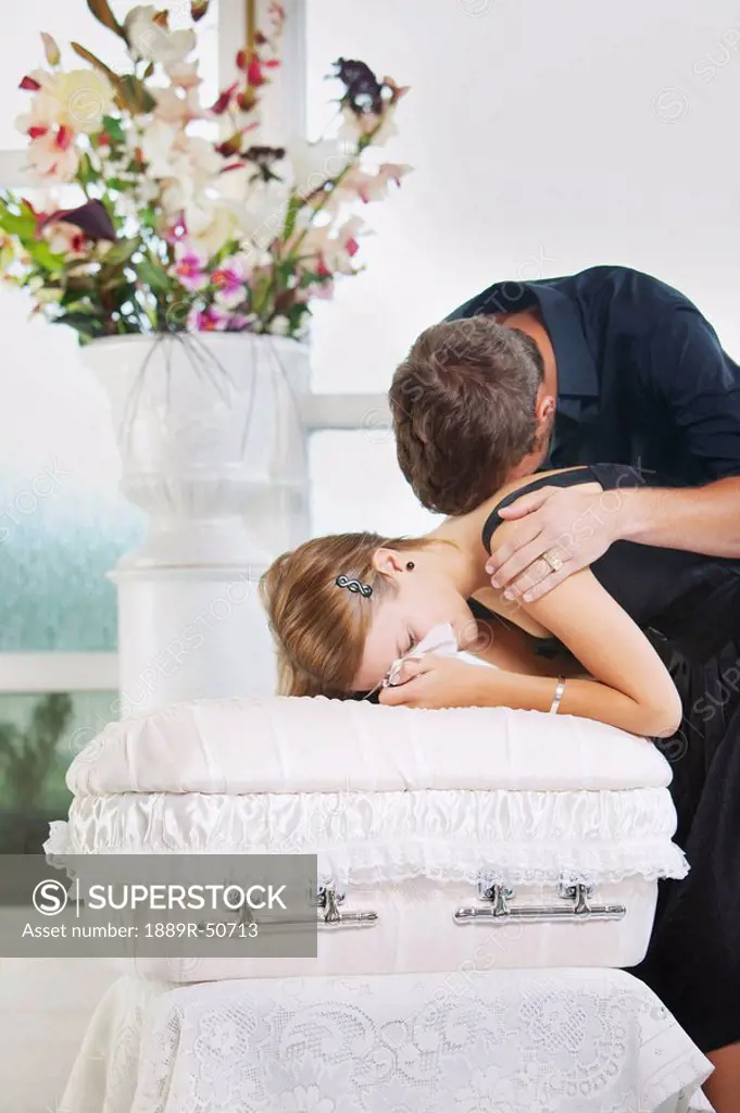 grieving young couple with an infant´s coffin