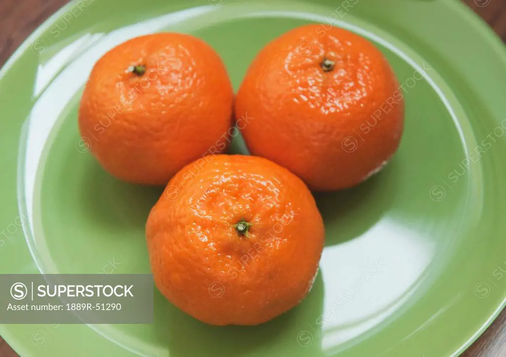 three oranges on a plate