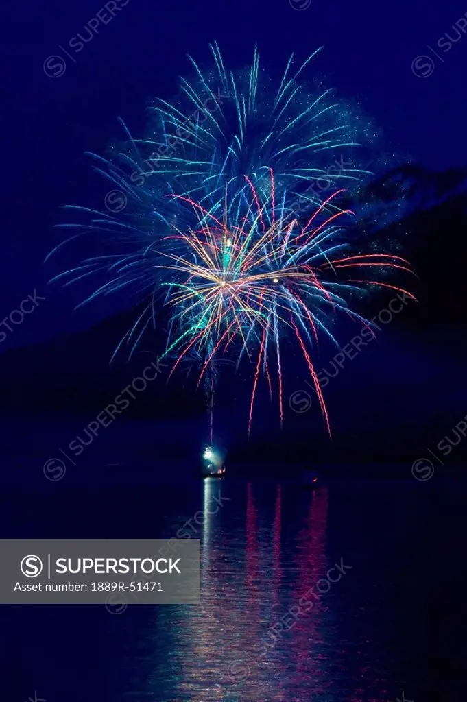 fireworks over the water with a mountain in the background