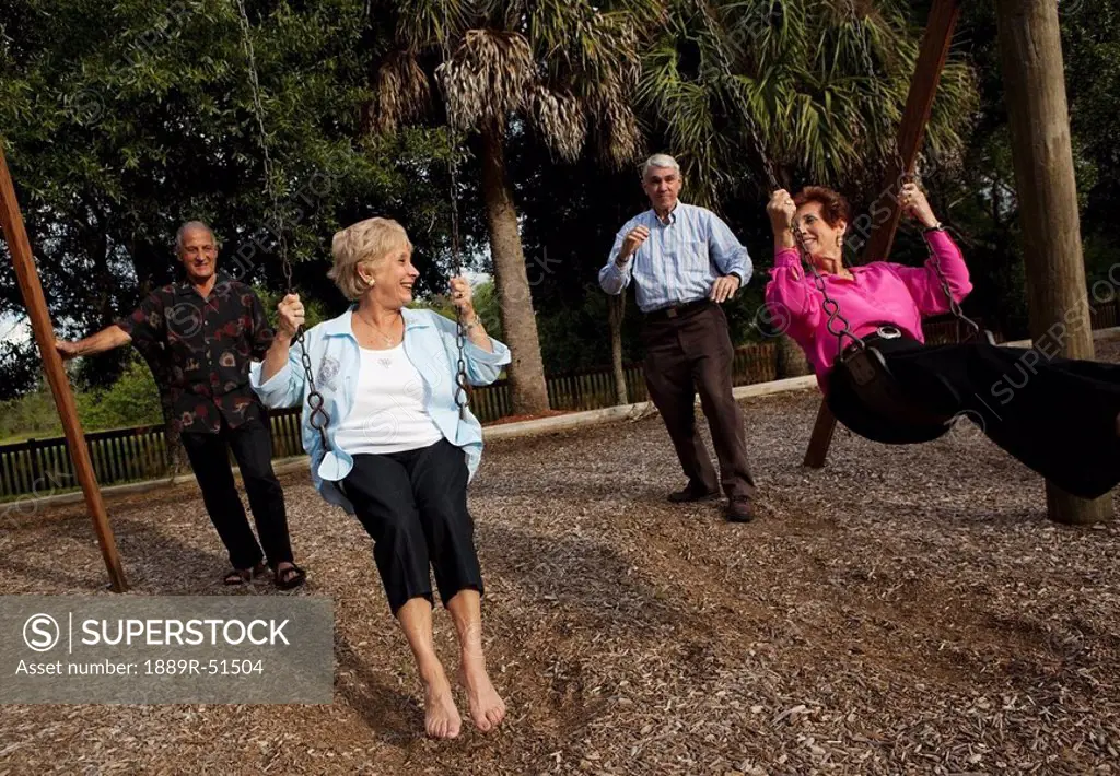 fort lauderdale, florida, united states of america, two married couples with the men pushing the women on the swings