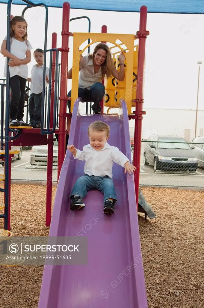 a mother playing at the playground with her three children