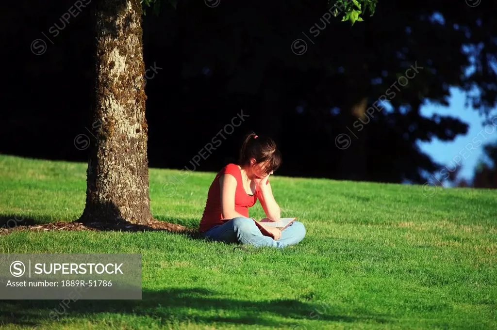 a girl reading a book in the park