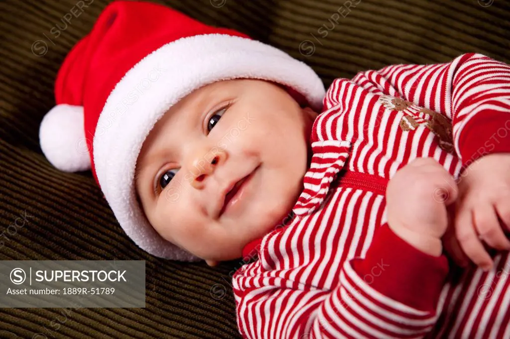 a baby wearing a red and white christmas sleeper and a santa hat