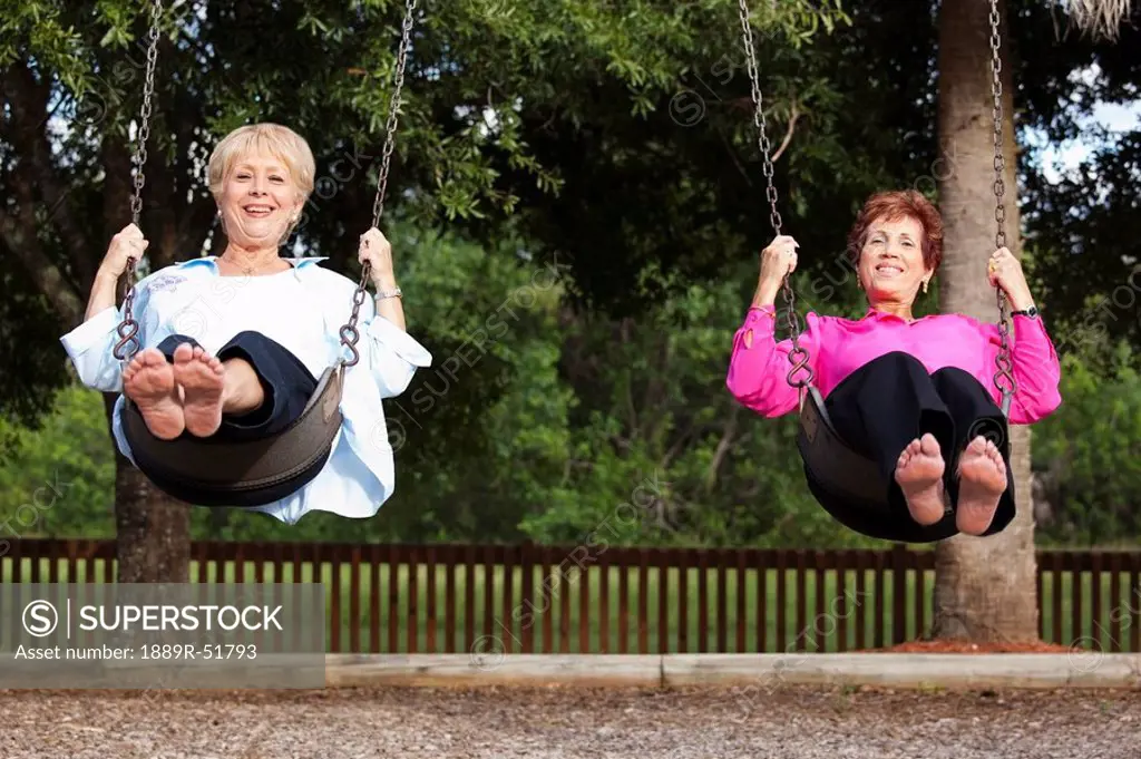 two women swinging on swings side by side
