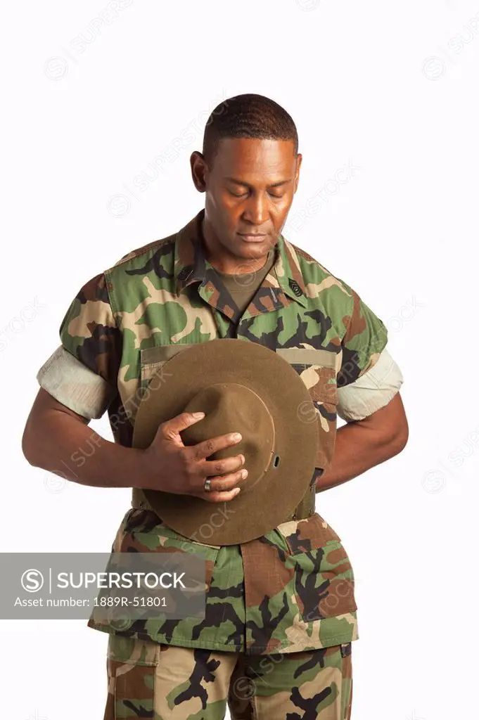 a military man holding his hat with his head bowed