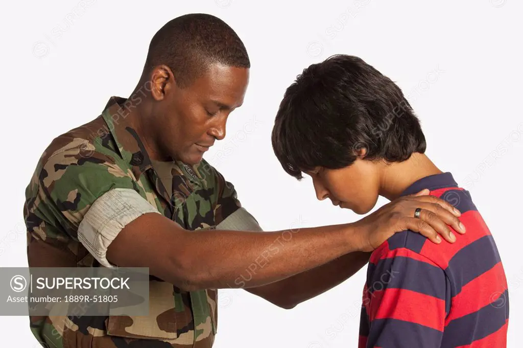 a military man praying for a teenage boy
