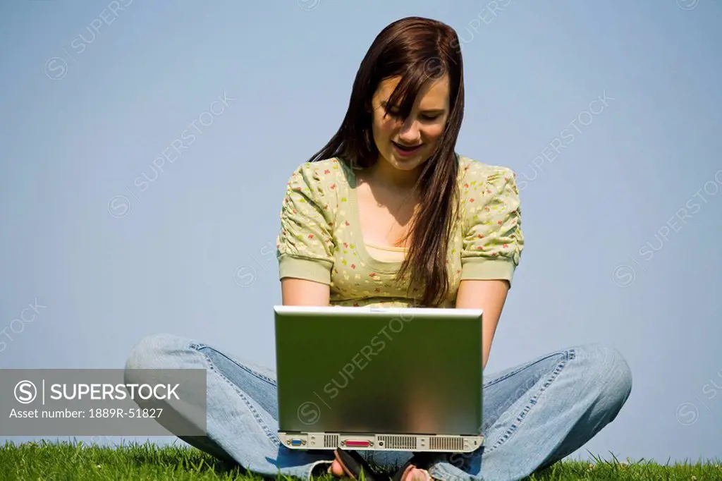 a girl working in the park on her laptop computer