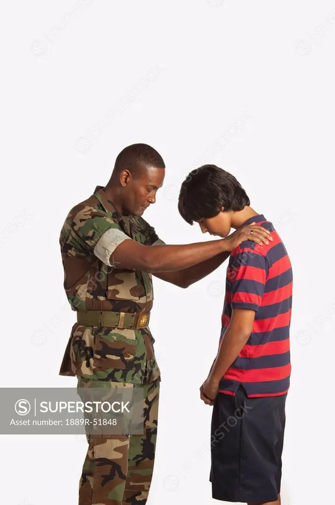 a military man praying for a teenage boy