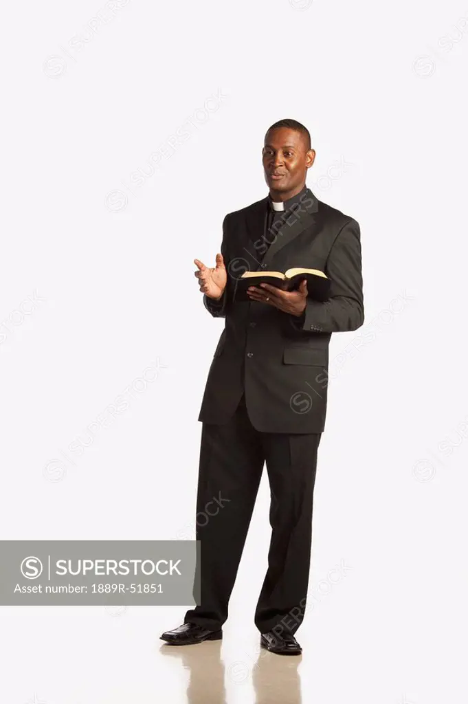 a man wearing a clerical collar and preaching from the bible
