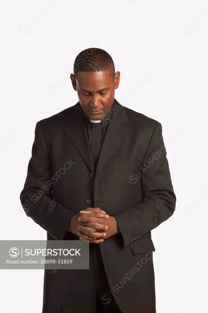 a man wearing a clerical collar with his head bowed in prayer