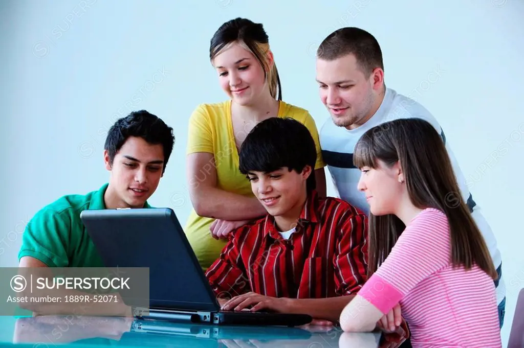 a group of teenagers looking at a laptop computer