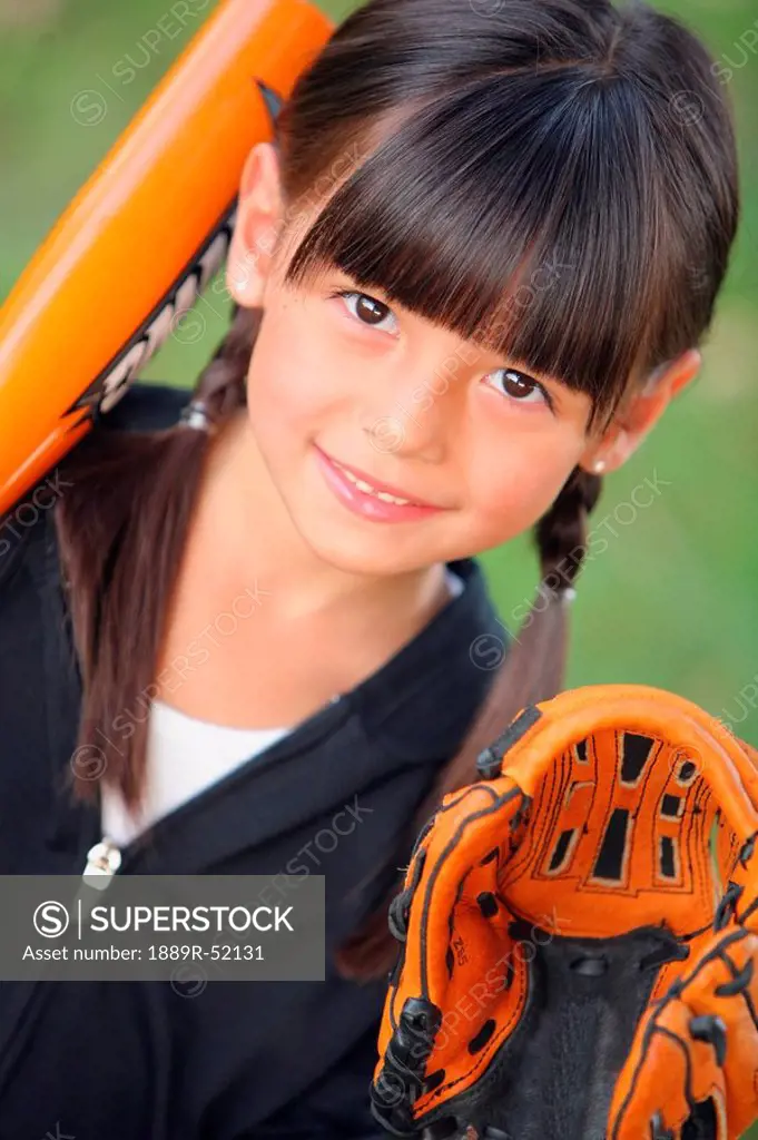 a young girl with a baseball bat and glove