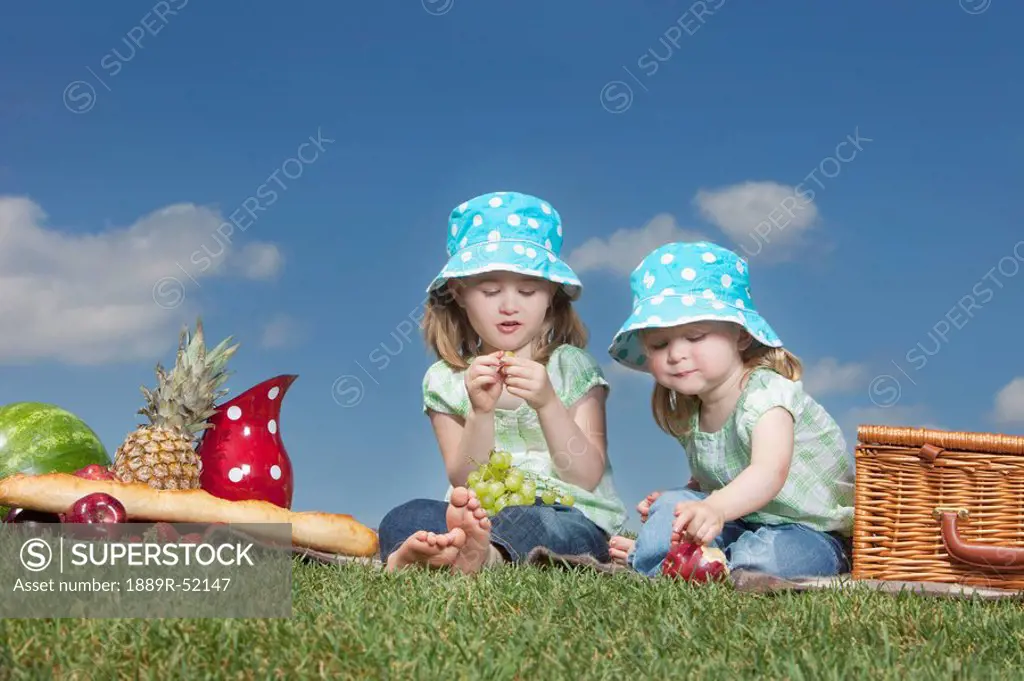 two young girls eating at a picnic