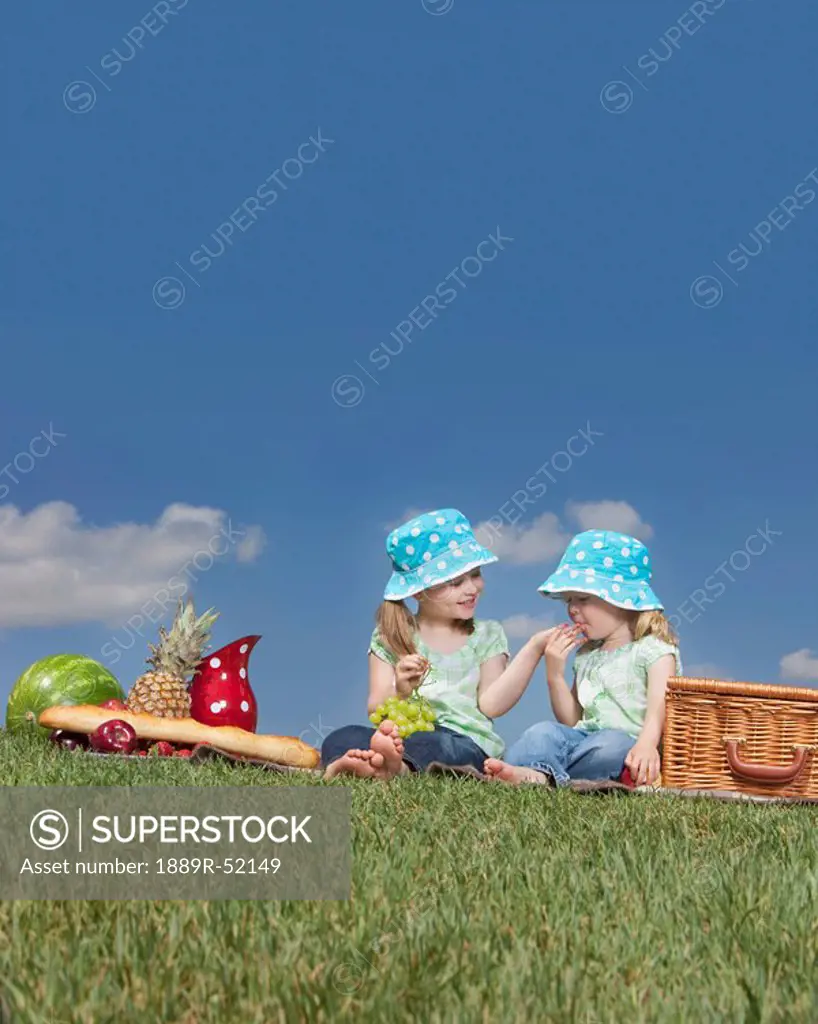 two young girls eating at a picnic