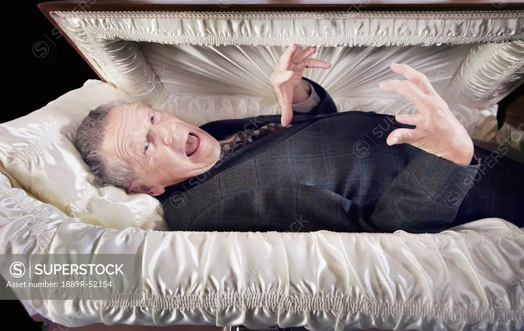 a man alive and laying in a coffin